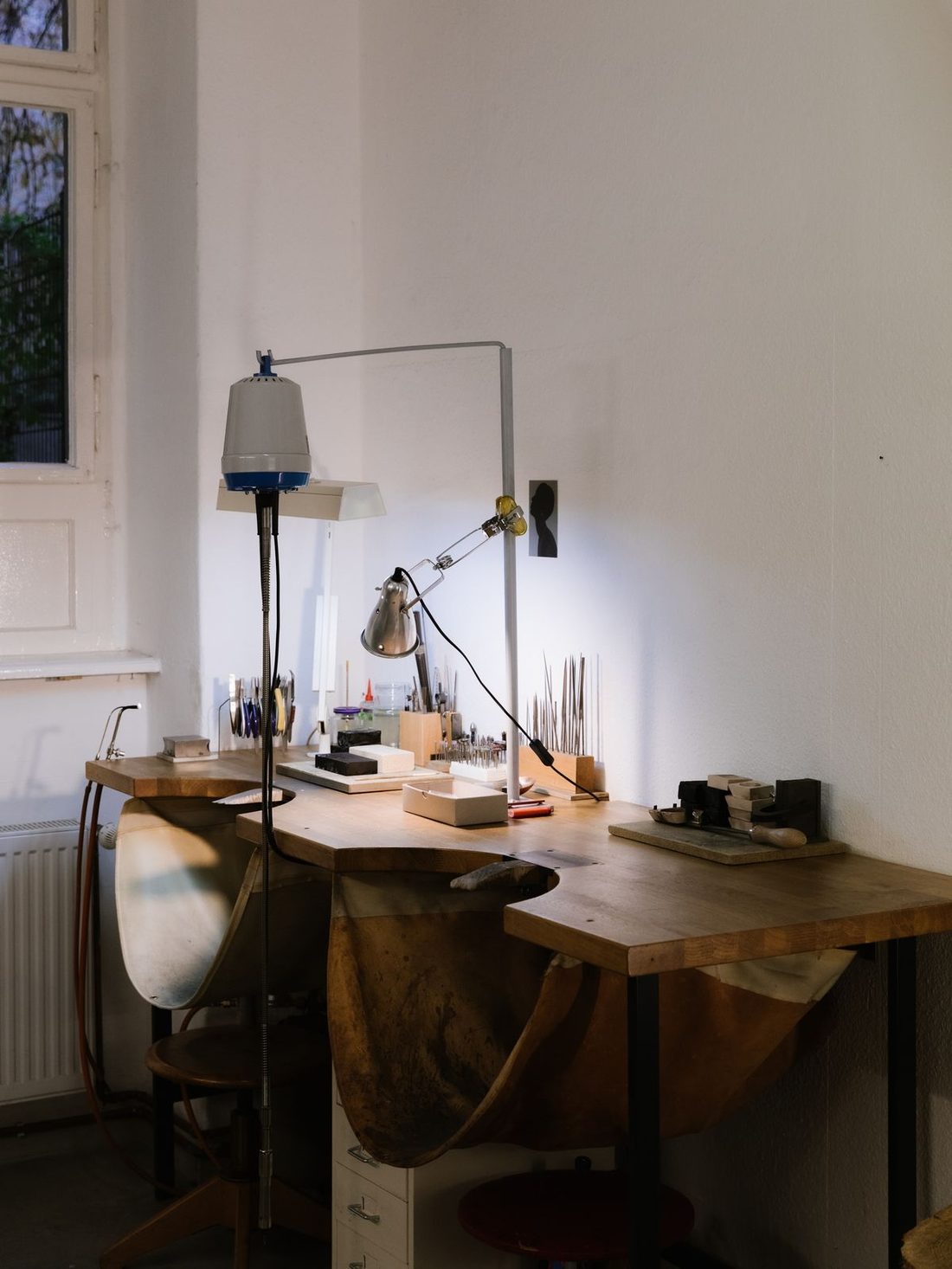 The studio bench where each piece is made, with hand tools and a work lamp